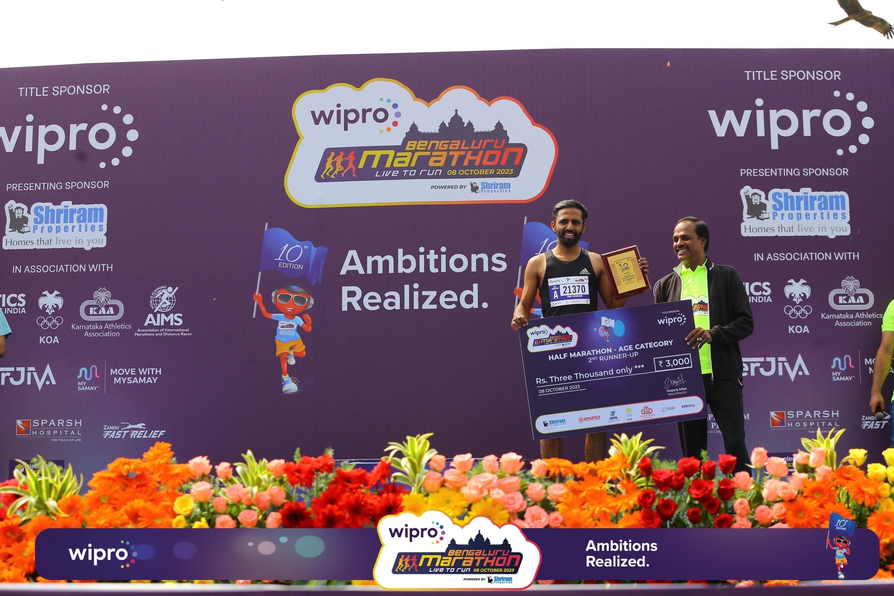 Coach Vikas Srinivasan on the podium at the Bengaluru Marathon