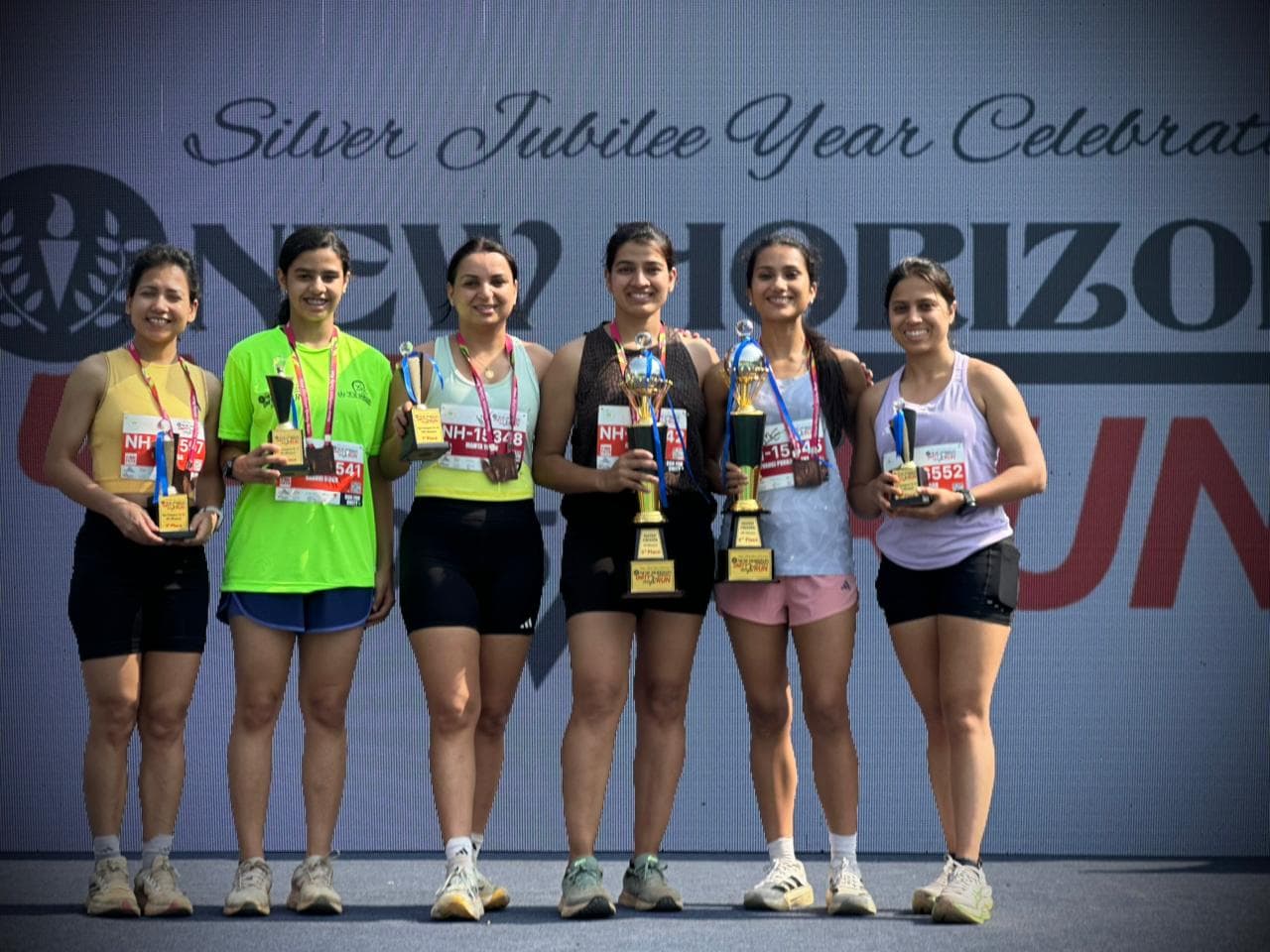 Runpundit women athletes with trophies at New Horizon Silver Jubilee Run 2026