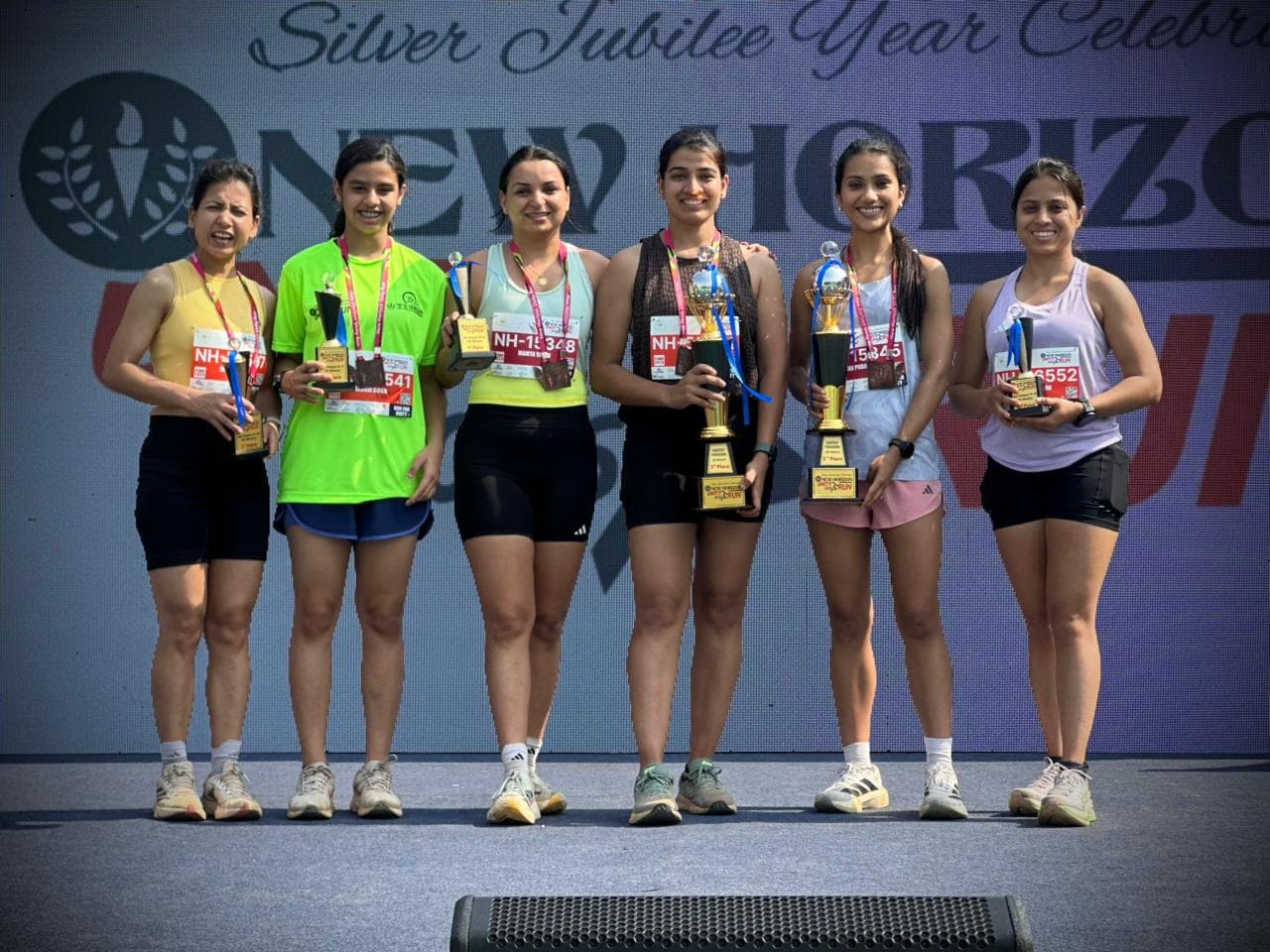 Runpundit women athletes with trophies at New Horizon Silver Jubilee Run 2026